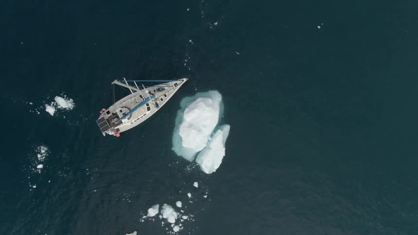 A birds eye view of a ship floating next to an iceberg in an ocean