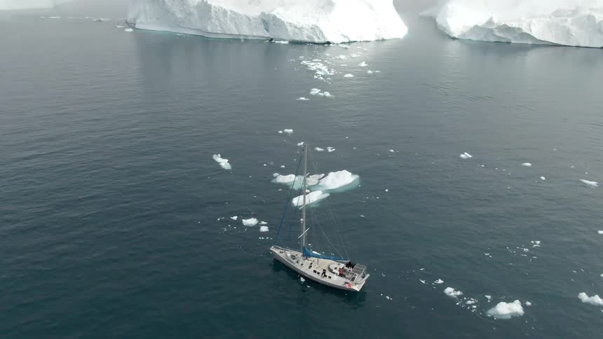 A boat floats in an ocean filled with ice and icebergs