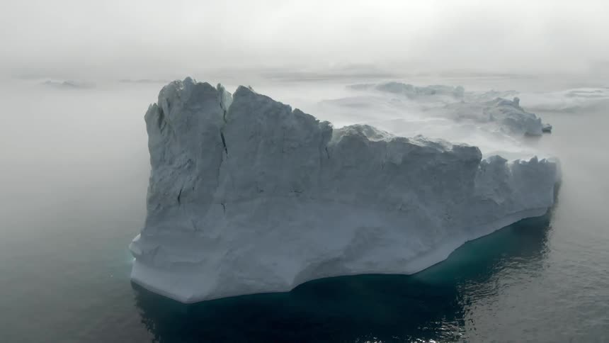 Large snow covered glaciers sit high above ocean water