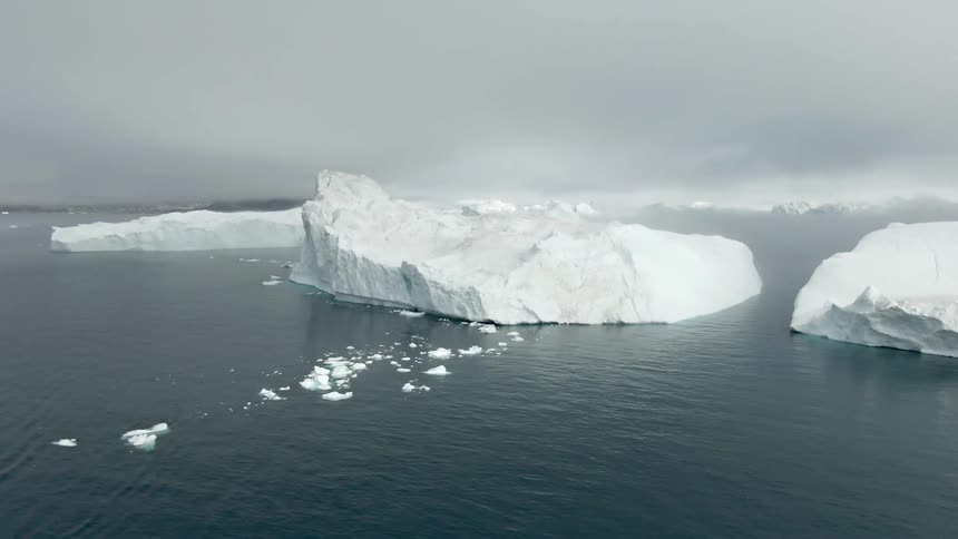Large pieces of ice float in the lake as smaller pieces float next to them