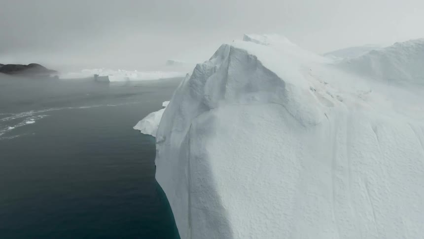 A large iceberg in the ocean on a cloudy and misty day