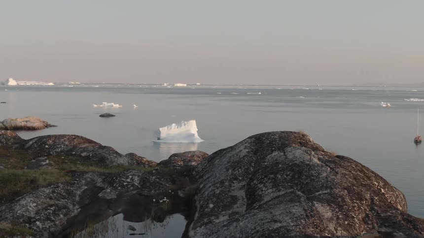 An aerial view of the water off the shore with icebergs and a boat in it