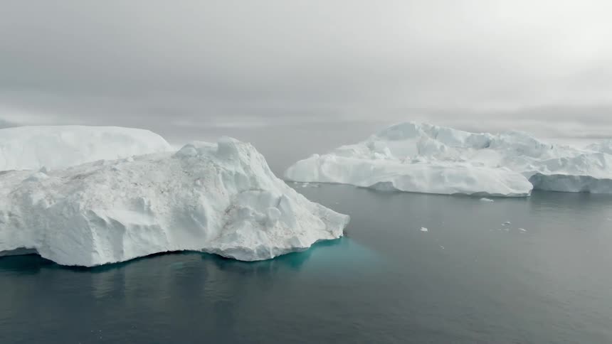 Small sections of an iceberg break off into the ocean