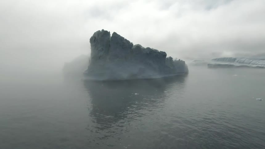 An aerial view of a boat in the ocean close to icebergs