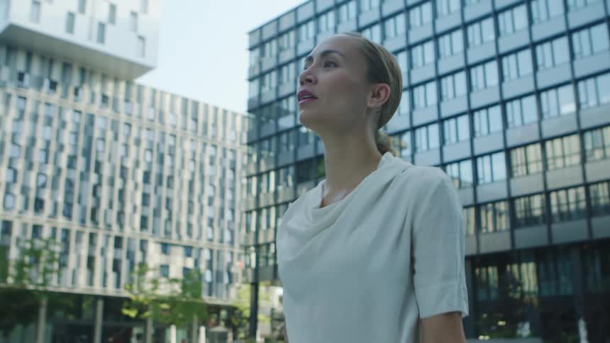 A woman is walking by herself in the city during the day and passing buildings