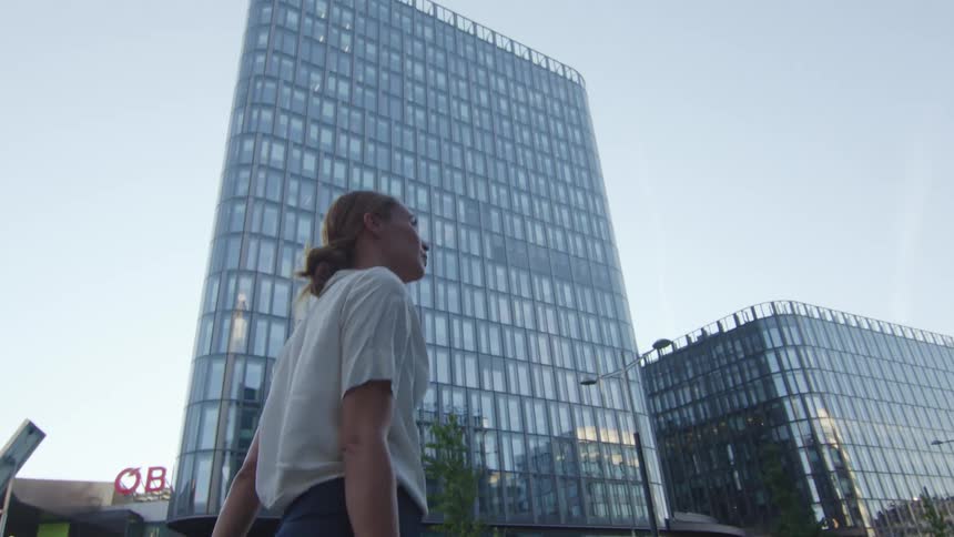 A woman walking past office buildings in a downtown area