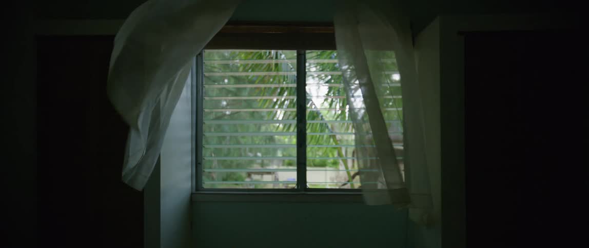 Short white curtains blowing in the wind coming through the open window