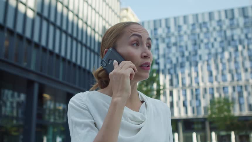 Woman outside large office building having conversation on cell phone