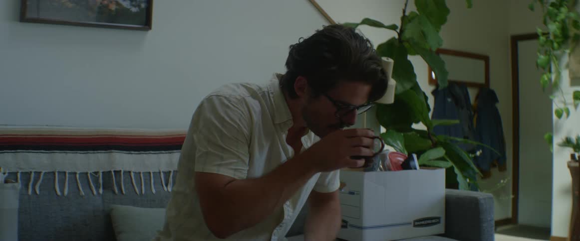 Man on a sofa in a living room drinking from a mug