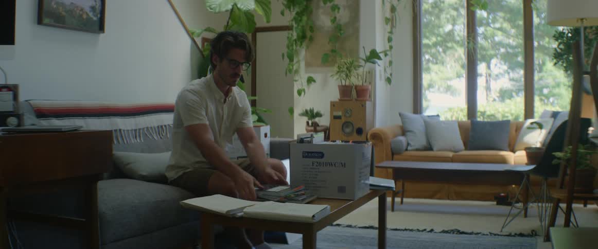 A man goes through a box full of notebooks pulls notebooks from box moves box