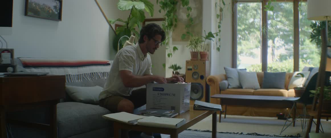 Man sitting down on sofa at home searching through files and folders in a box