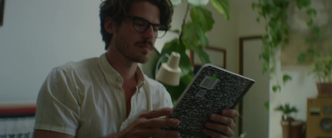 A man looks through a box and picks out a notebook then places it down on a table