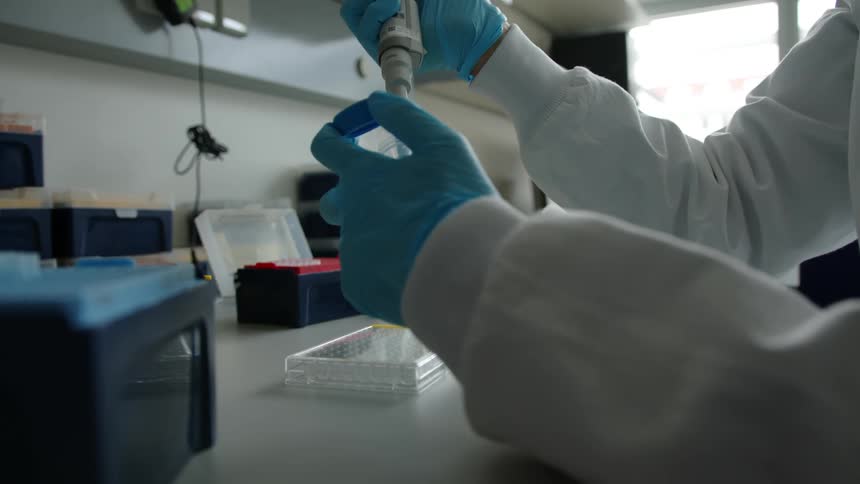 White coated person deposits contents of dropper into specimen jar