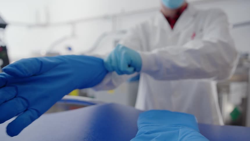 A person in a lab puts on goggles and gloves