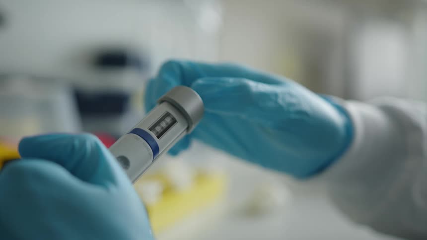 A woman in a lab turns a dial on a tube