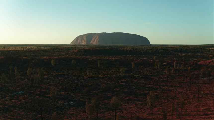 Aerial pushing straight towards Australia's Uluru at sunrise