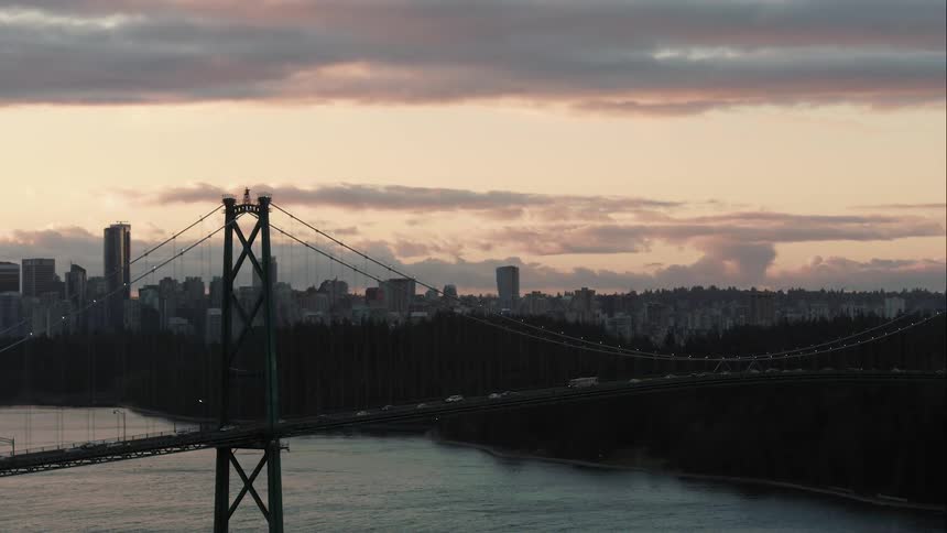 Lions Gate Bridge at sunrise with Vancouver city skyline in the background