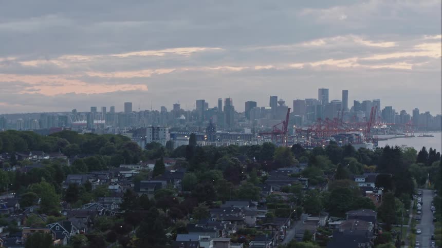 Aerial rises and tracks to reveal downtown Vancouver and port at dusk