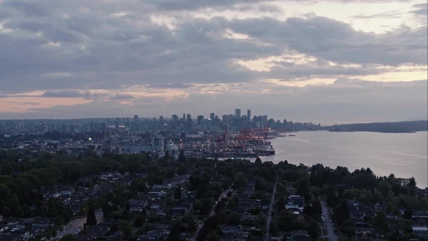 Aerial pushes in and rises revealing downtown Vancouver city skyline at dusk