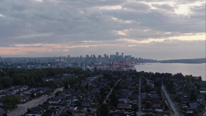 Aerial pushes in towards downtown Vancouver and port at dusk