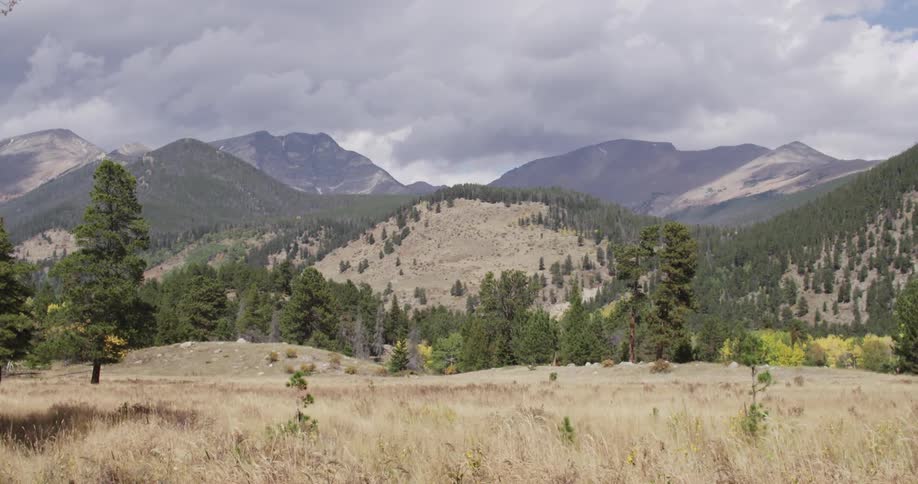 A large grass field leads to a mountain range