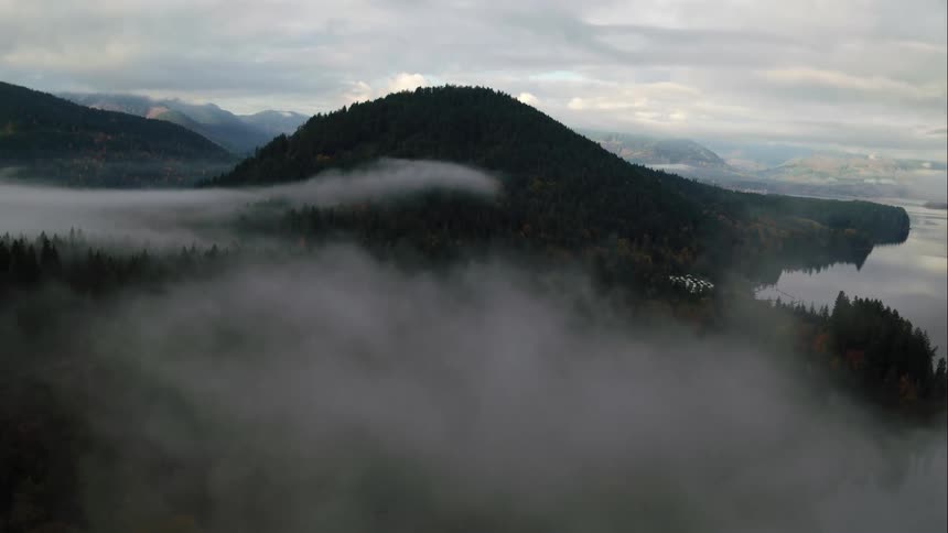 Pushing through fog towards mountain by a lake