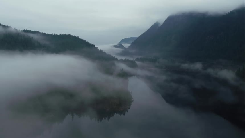 A fog shrouded valley between mountains covered in forest