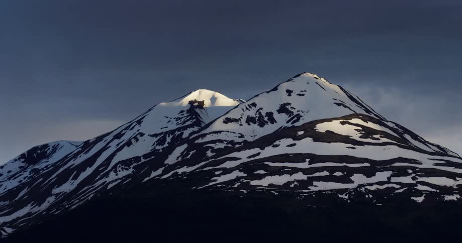 Clouds cast shadows on a mountain range covered in snow