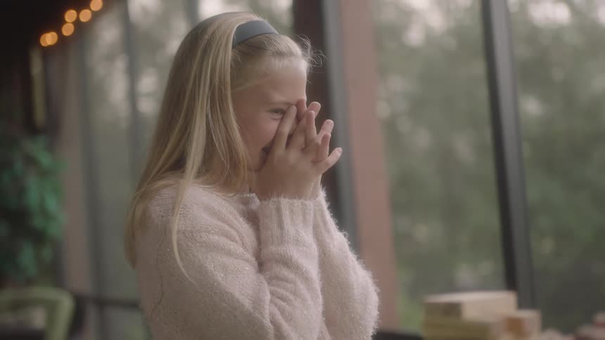 A blonde girl seems a excited and holds hands to face