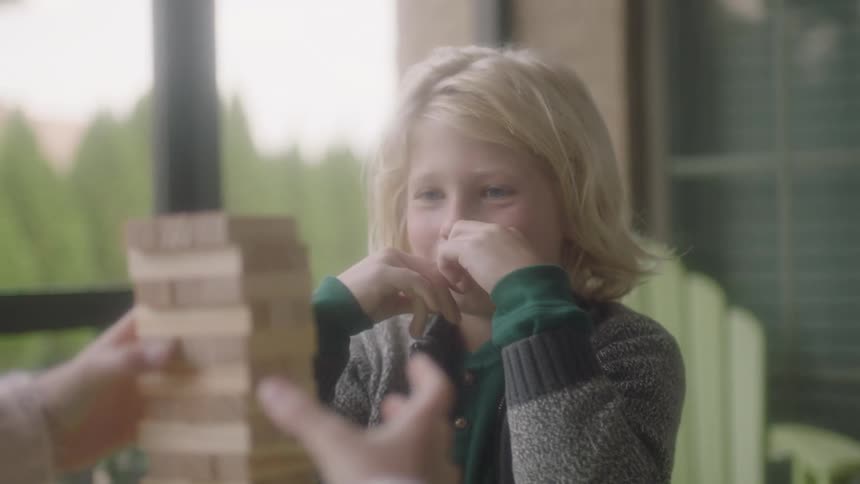Three children are sitting at a table as they play a game with wooden pieces
