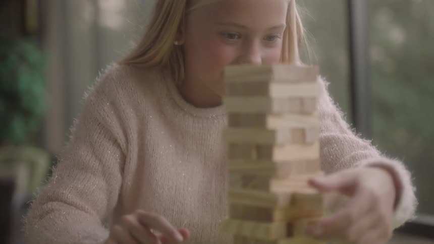 A little girl smiles as she takes her turn when playing a game with her mother
