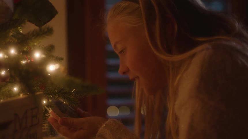A girl examines a decoration on a christmas tree