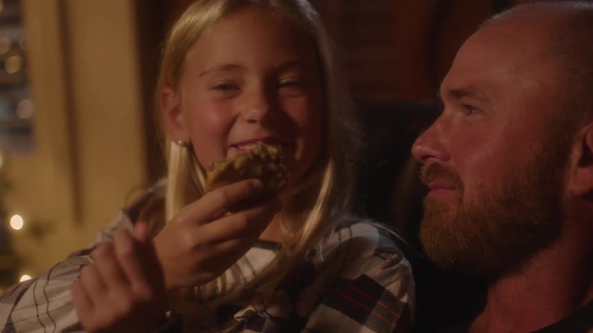 Father and daughter sit together and share a cookie
