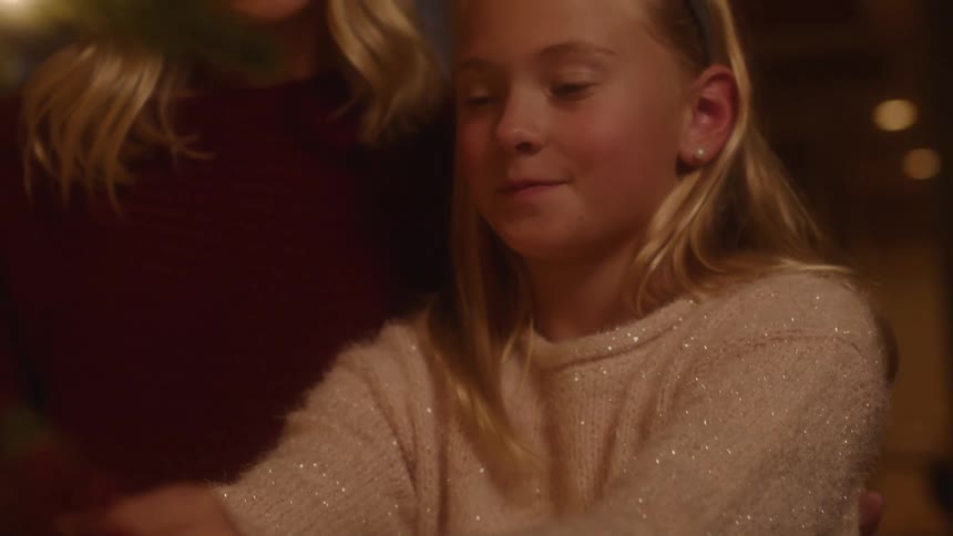 A woman hands a young girl an ornament