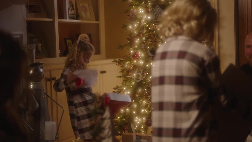 Children tear open their presents in front of their father and a christmas tree