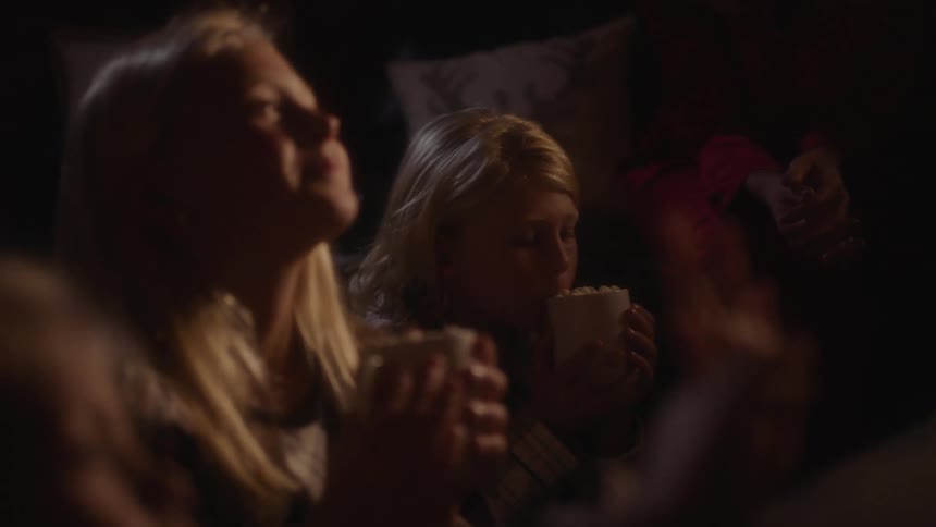 A young girl throws her head back and smiles after drinking from a mug