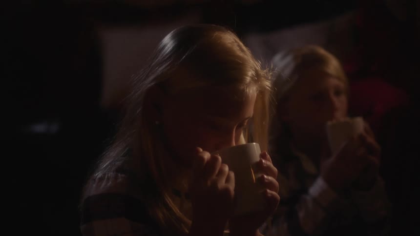 A girl in a room holding a mug sipping on hot chocolate
