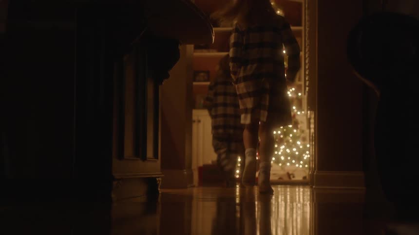 A group of children run excitedly to a christmas tree