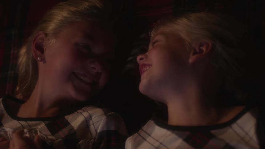 Two sisters laying down and laughing together