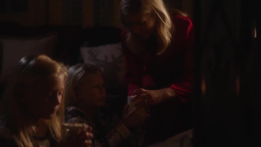 Mother and children sit in living room drinking warm beverages
