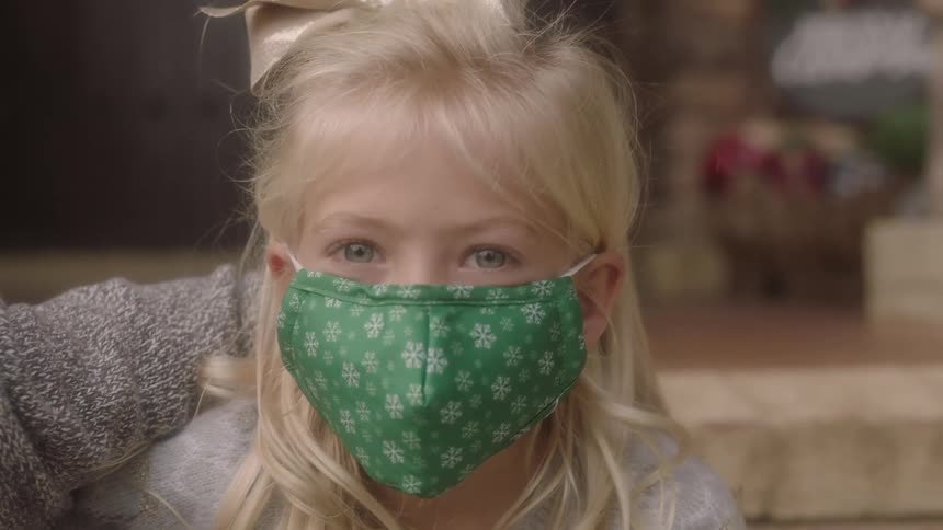 Little girl sitting down wearing a face mask