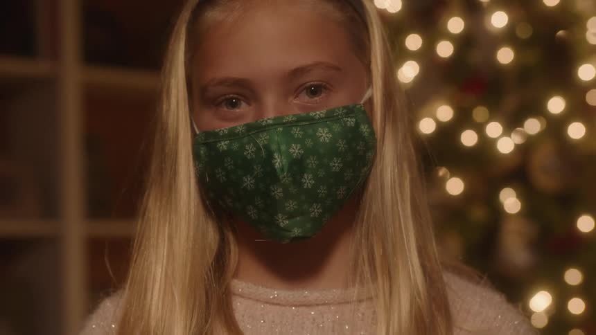 A girl wearing a face mask looks up at the camera