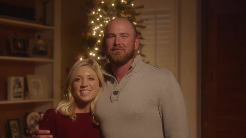 A couple stand together in front of the christmas tree