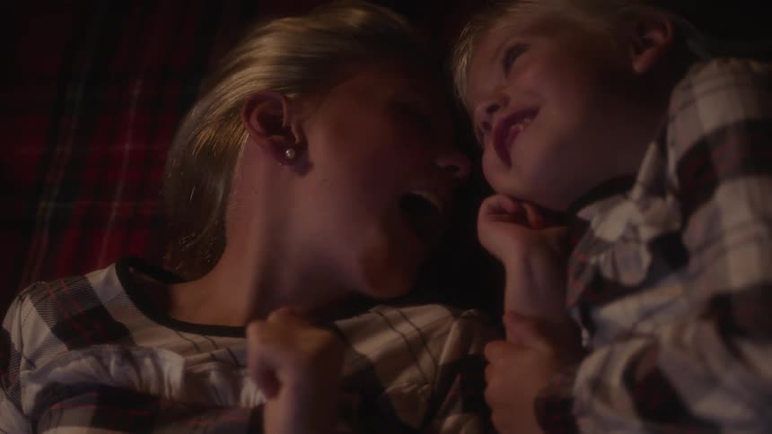 Three sisters lie next to each other laughing and talking