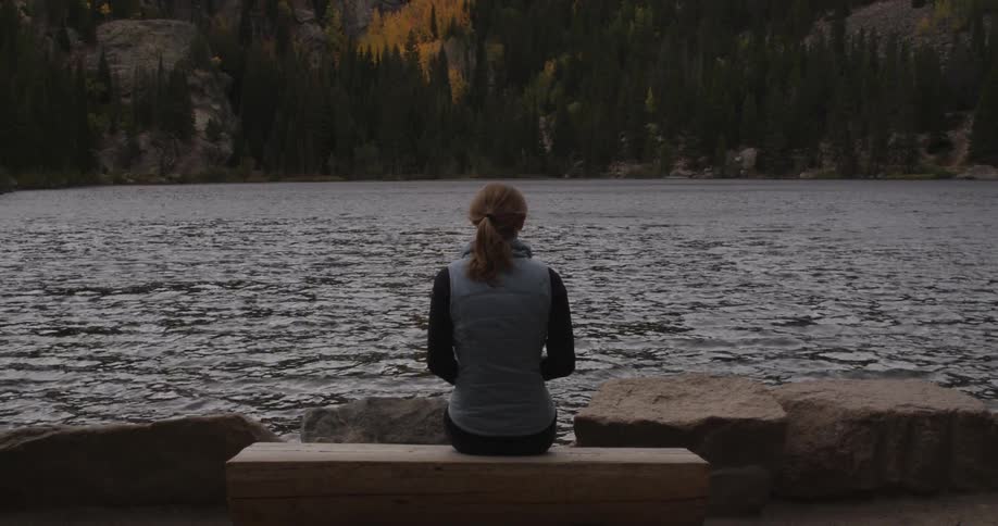Woman sits on a bench beside a lake