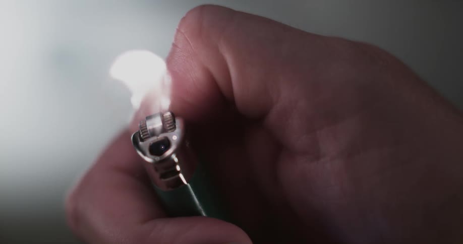 A hand sparks a lighter as a flame goes up