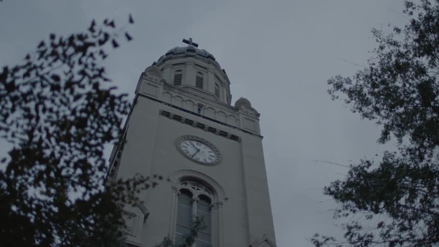 Church tower with a clock on the front and a cross on top