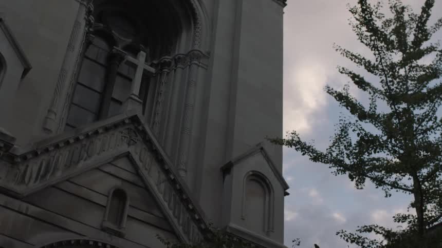 The outside of a stone church on a cloudy day