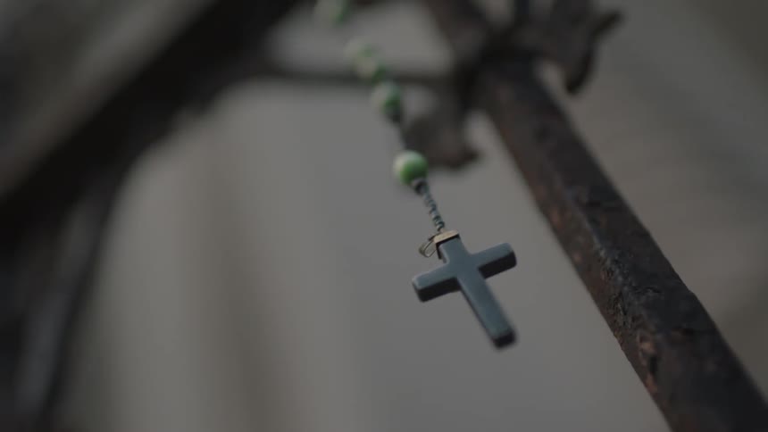 A rosary hanging from an iron fence