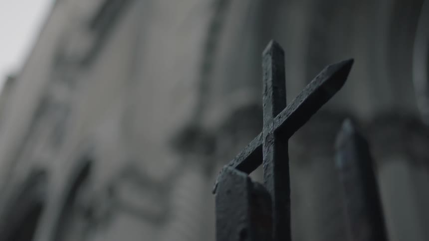 A metal cross stands in front of a church